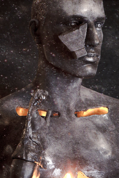 Illuminated reclaimed mannequin with a dark metallic face and stone detail in Fallen Memorial by Melanie Winning